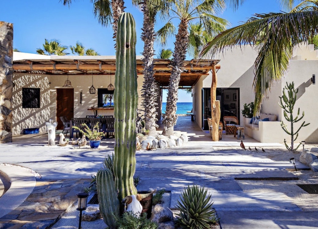 Exterior courtyard of Casa Tres Palmas with desert landscaping, palms, and ocean view