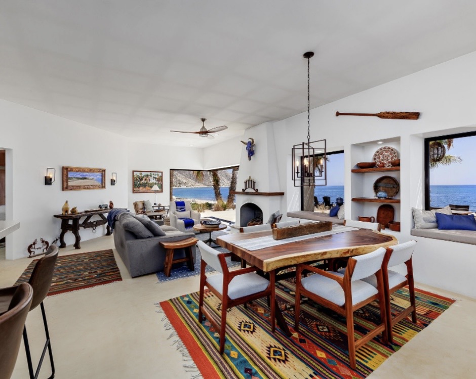 Open-plan living and dining room with local art, wood dining table, and ocean views