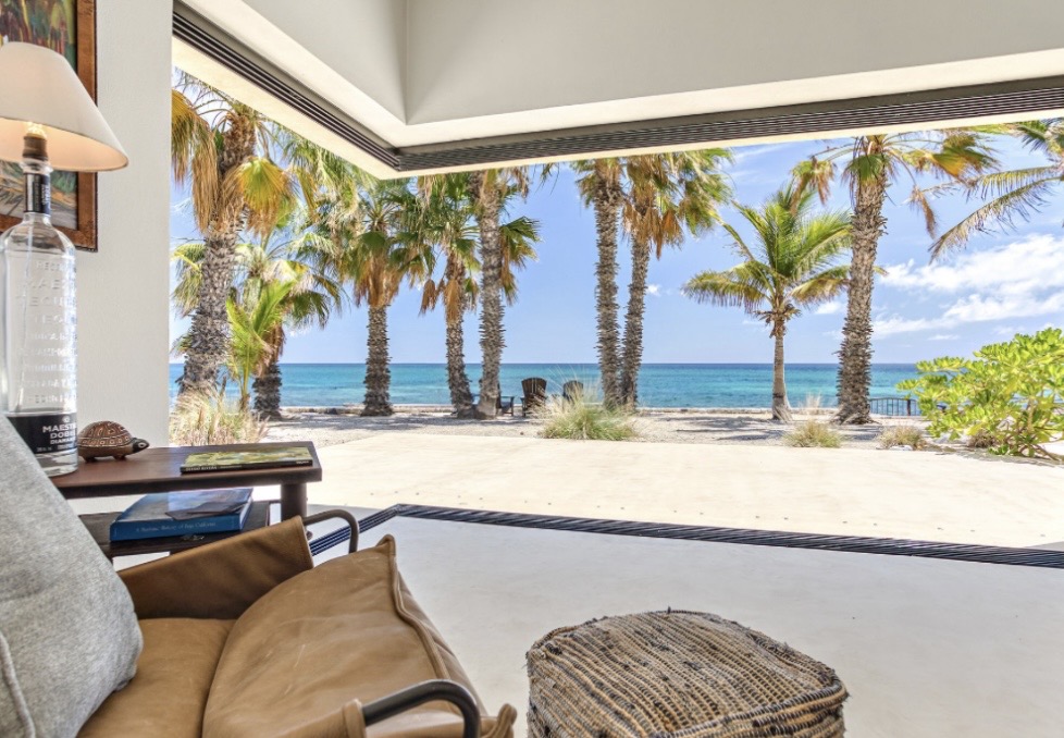 Living room with sliding wall fully open to palm trees and the Sea of Cortez