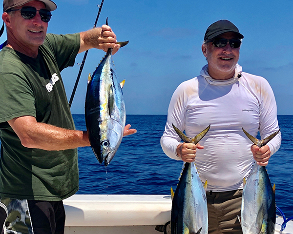Two anglers holding freshly caught yellowfin tuna on a fishing charter